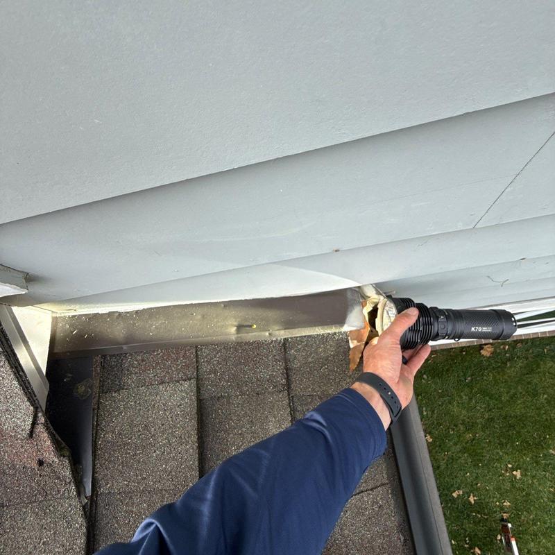 Ridge vent inspection with flashlight on shingle roof