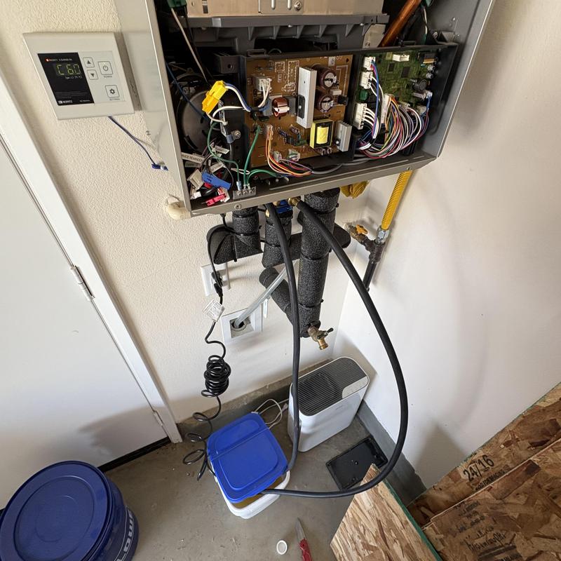 Tankless water heater with open control panel and hoses