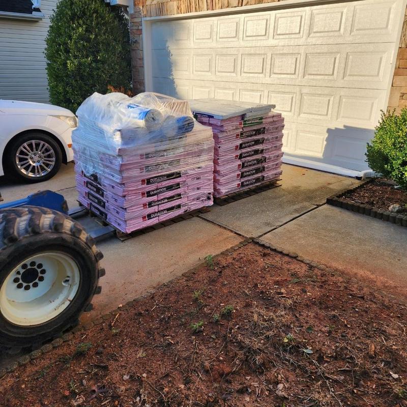 Architectural roofing shingles stacked on driveway