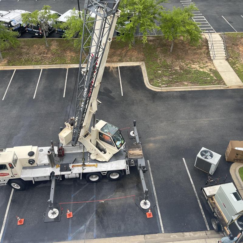 10-ton heat pump condenser on crane in parking lot