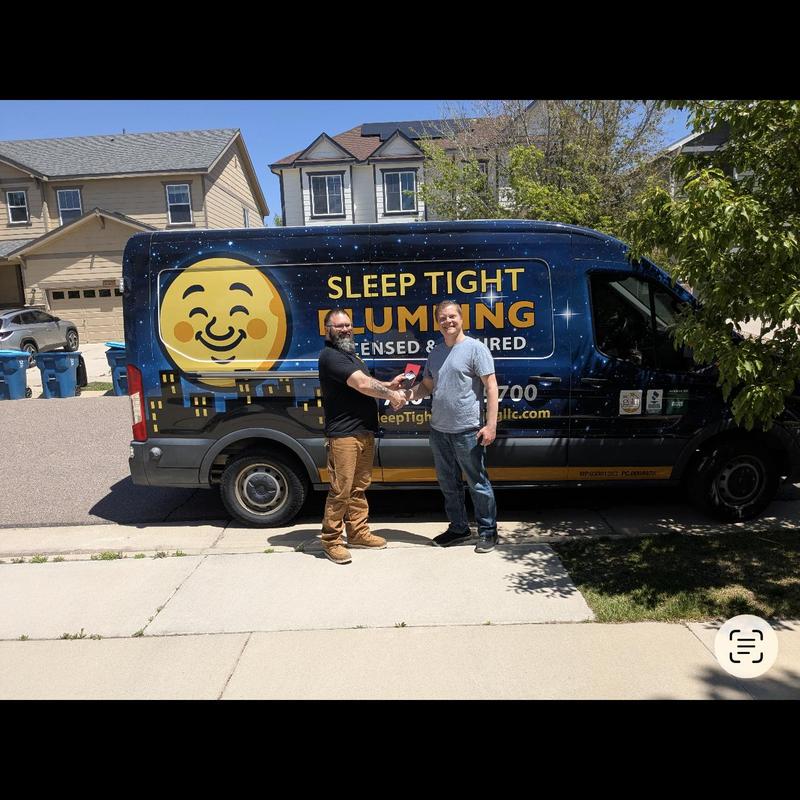 Plumbing service van with two men shaking hands outside house