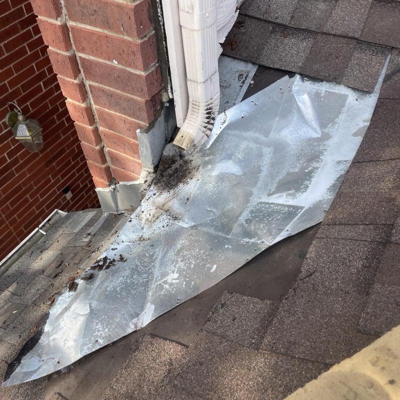 Chimney flashing and gutter downspout on roof