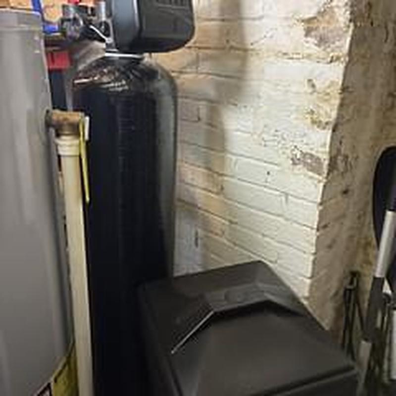 Water softener unit installation in basement corner