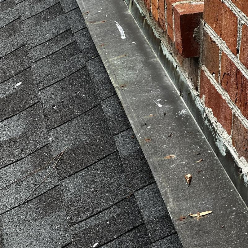Roof flashing along brick chimney on shingled roof Roof flashing along brick chimney on shingled roof