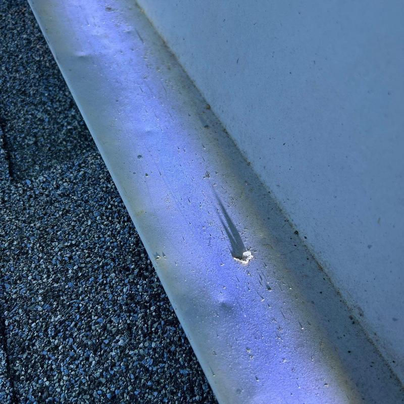 Metal flashing with hail damage dents and puncture
