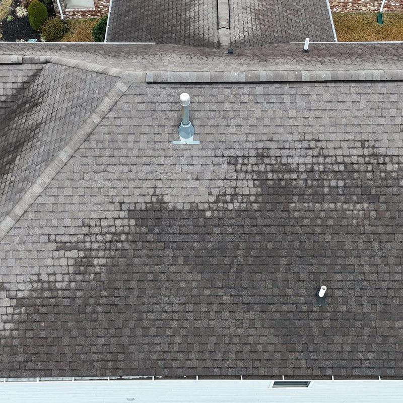 Asphalt shingle roof with discoloration and vent pipes