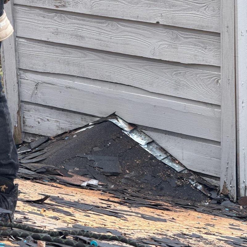 Roof shingles and flashing with damage at wall base