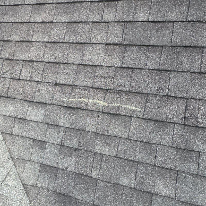 Asphalt shingle roof with chalk-marked damage area Asphalt shingle roof with chalk-marked damage area