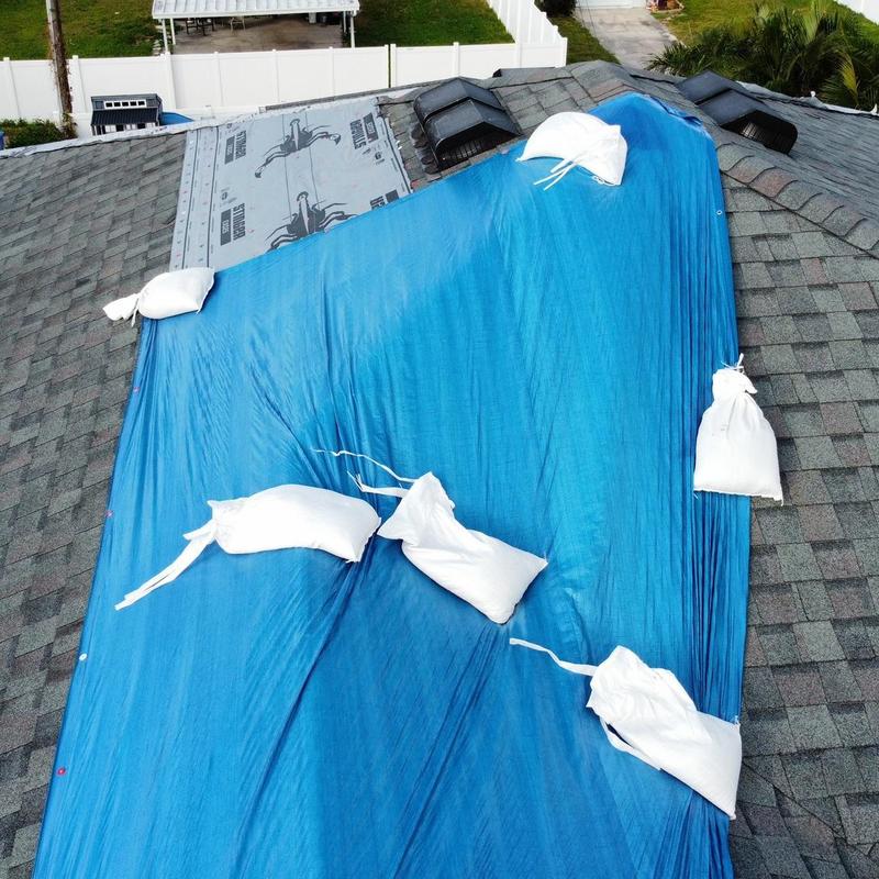 Roof tarp with sandbags on storm-damaged shingles Roof tarp with sandbags on storm-damaged shingles