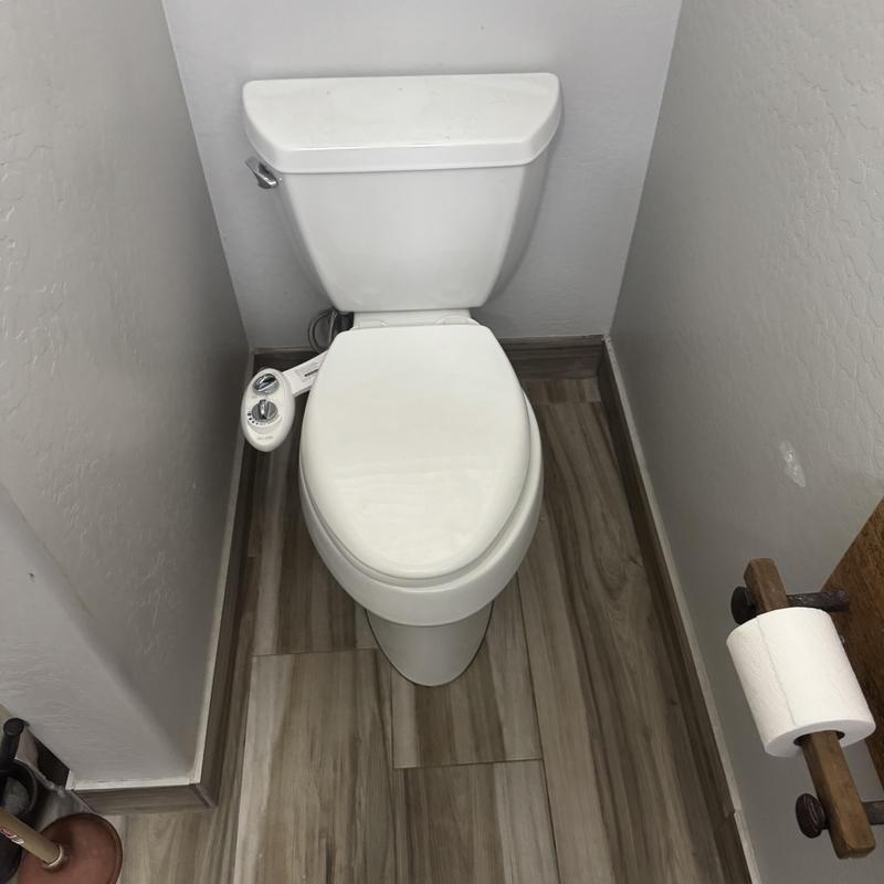 Toilet with bidet attachment installation in bathroom corner