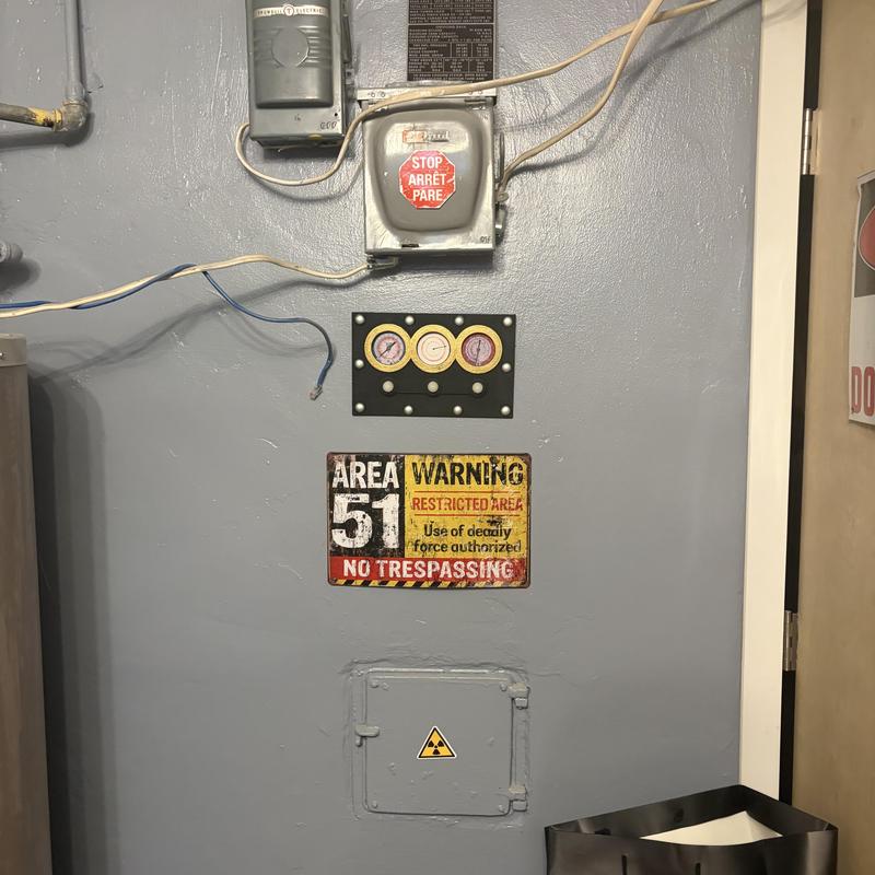 Electrical meter and gauges on gray wall with warning signs