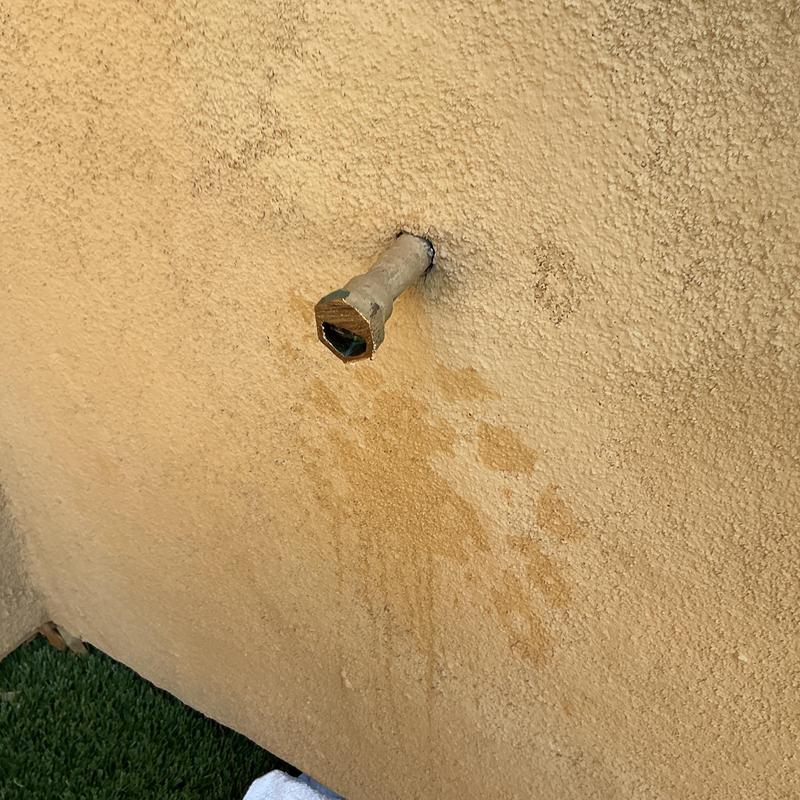 Outdoor hose bib pipe protruding from stucco wall