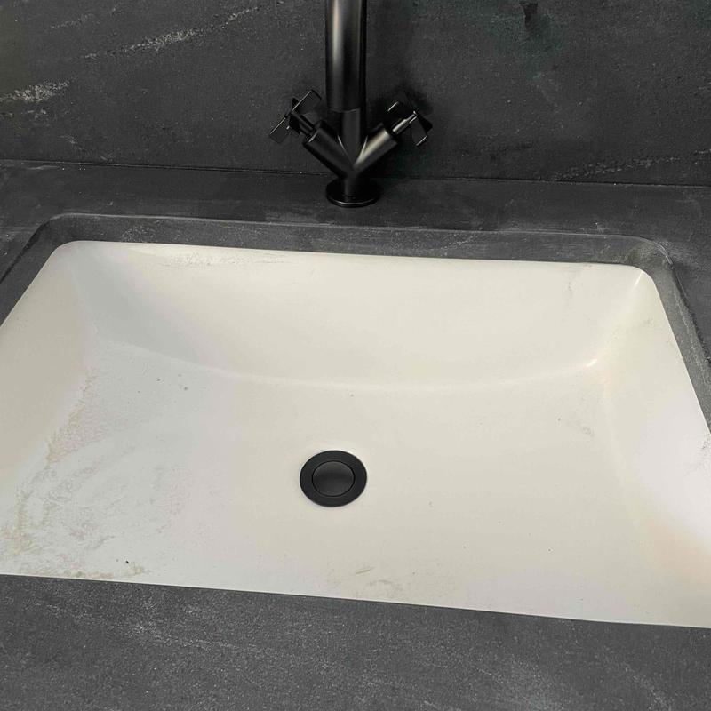 Bathroom sink with matte black faucet and drain cover