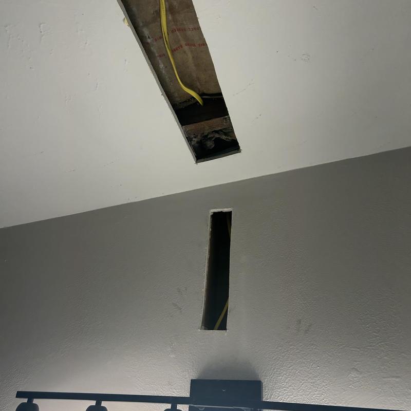 Ceiling and wall sheetrock cut for exhaust fan wiring