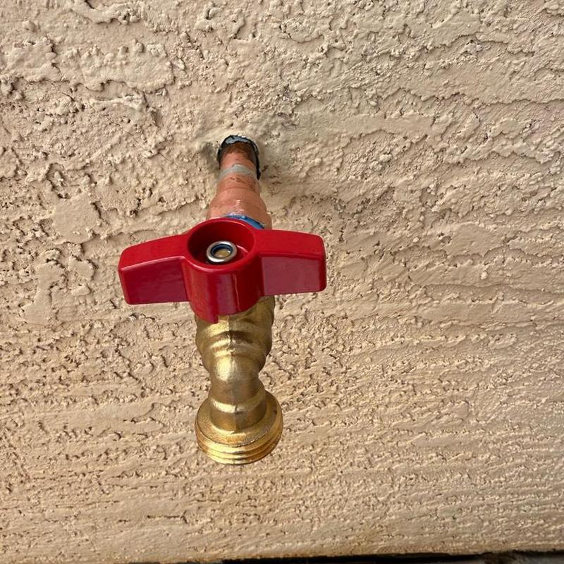 Hose bib with red handle installed on wall Hose bib with red handle installed on wall