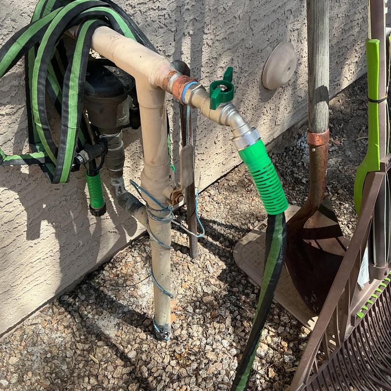Outdoor hose bib with green garden hose attached