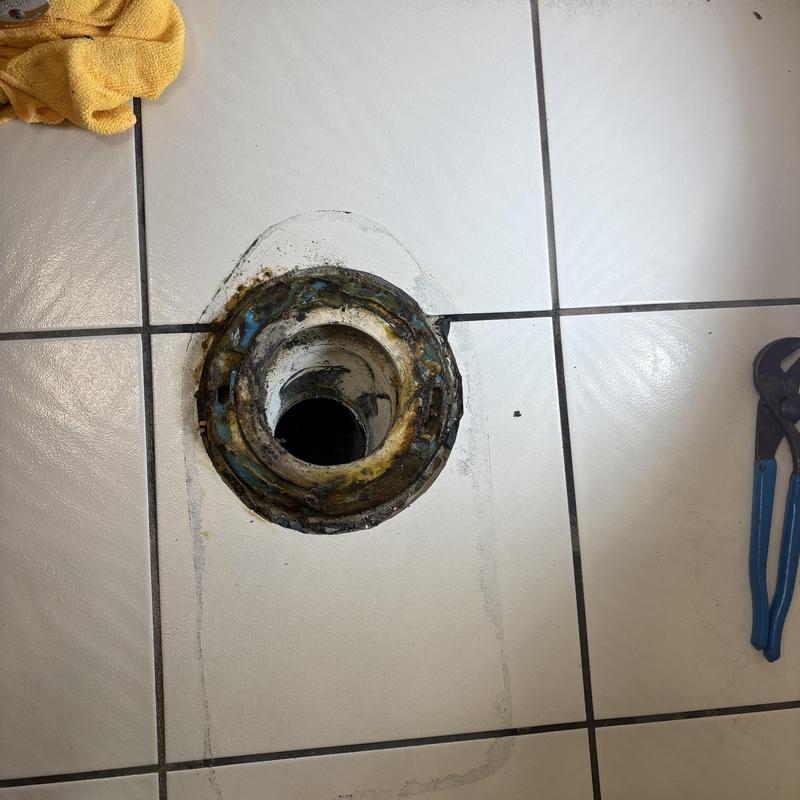 Toilet flange on tiled floor with tools nearby