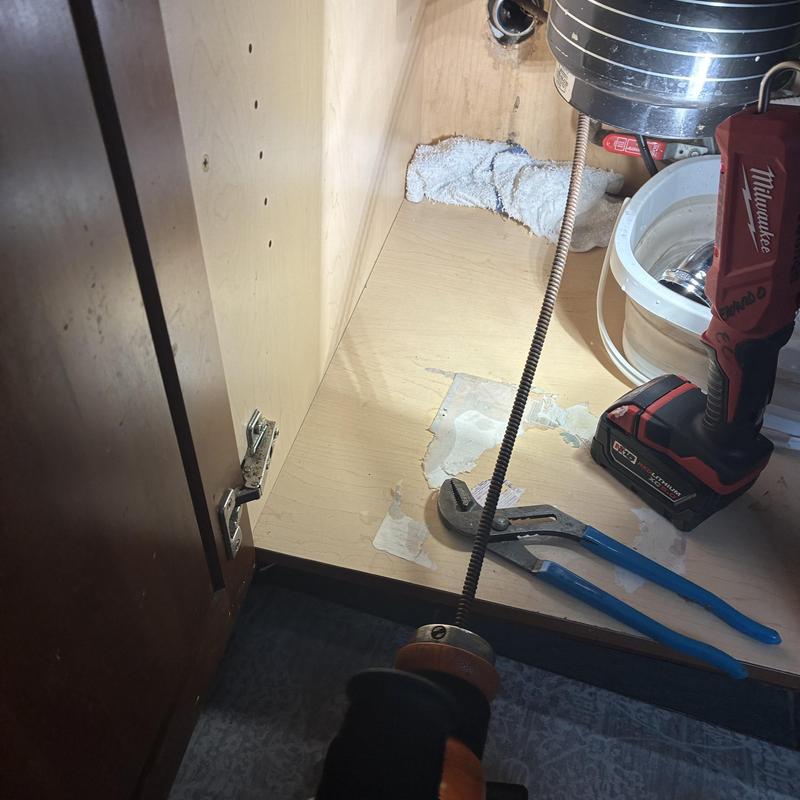 Kitchen sink drain line with plumbing tools and cable