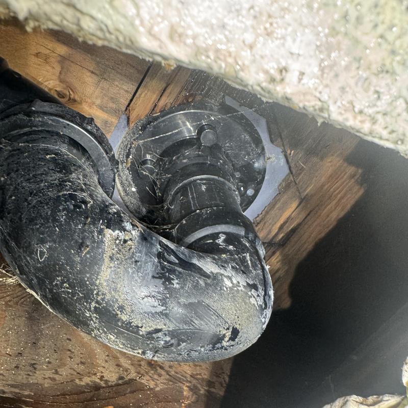 Bathroom drain pipe under floor with grime buildup