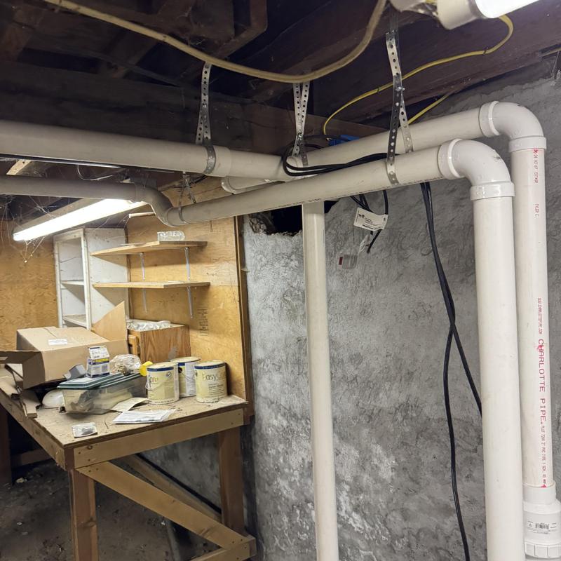 Sewage ejector pump PVC piping and basement workspace