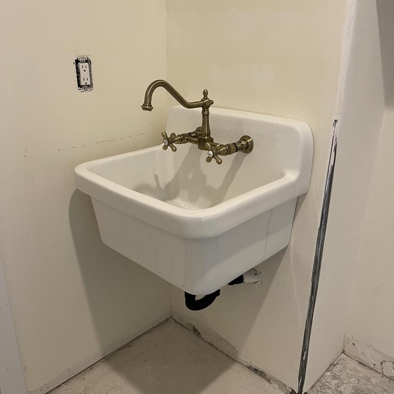 Wall-mounted laundry sink with brass faucet installation