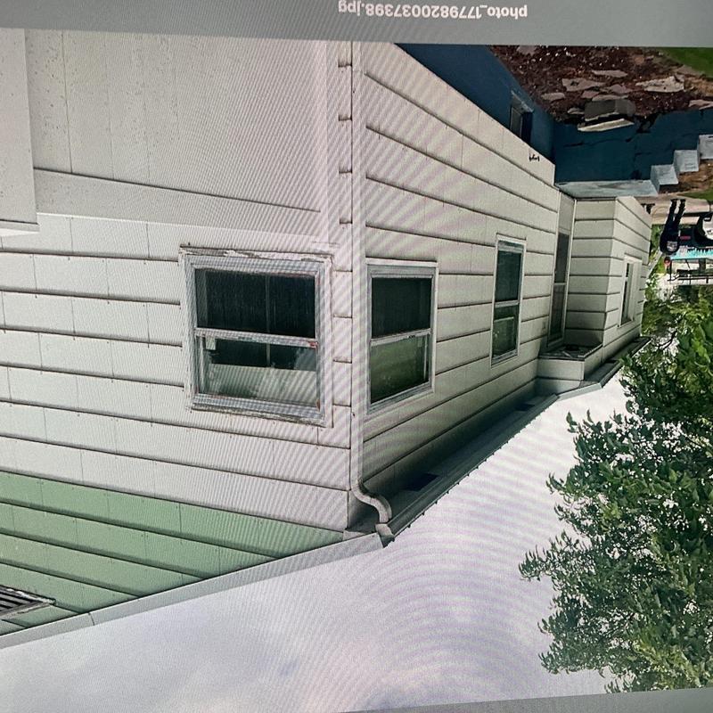 Gutter system along white house exterior with windows Gutter system along white house exterior with windows