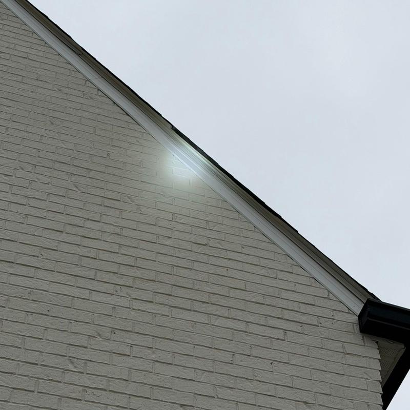 Roof flashing with hail damage on brick wall edge