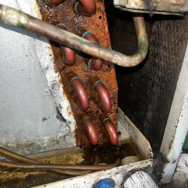 Rusty copper coils with corrosion and buildup inside HVAC unit