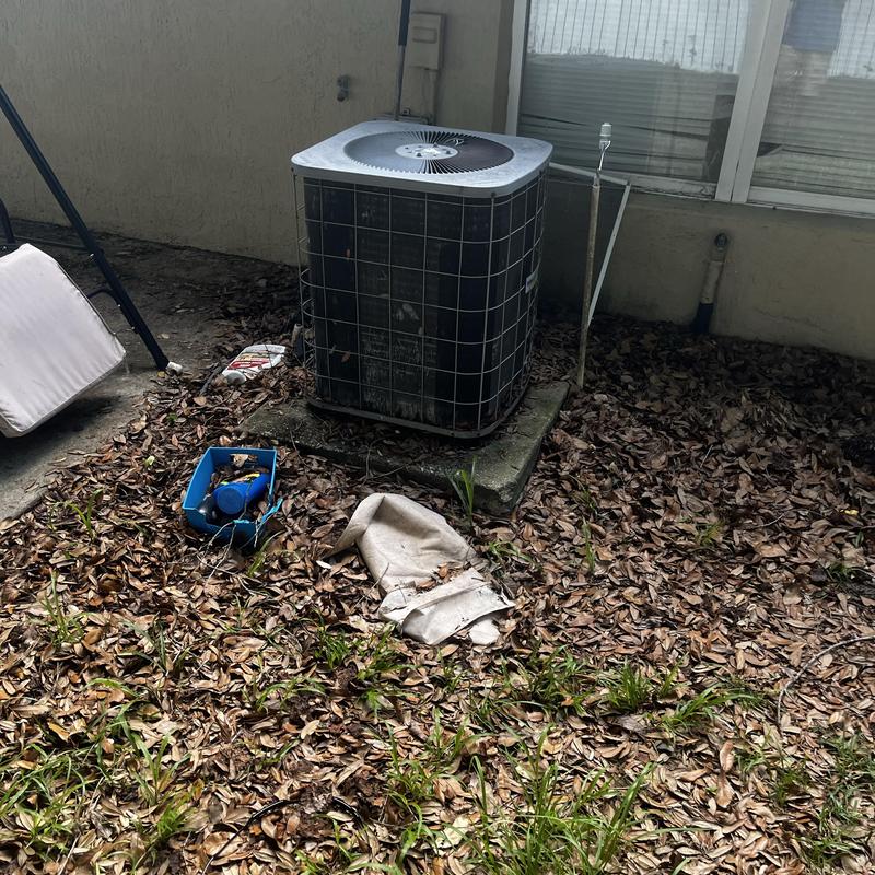 Outdoor AC unit with impacted coils and debris nearby