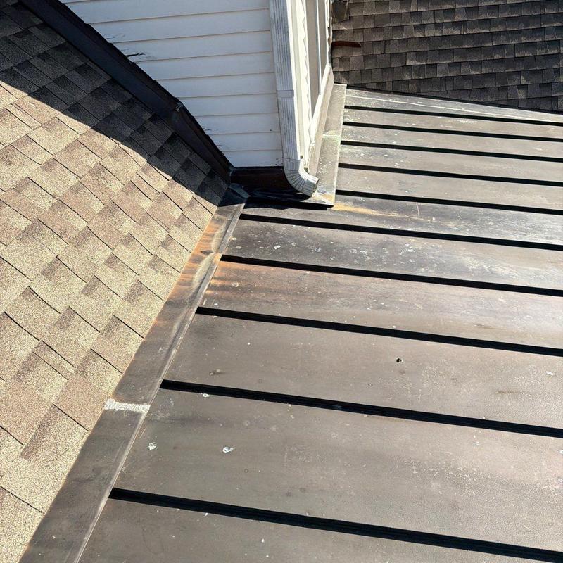 Metal roofing panels with adjacent shingle roof and flashing