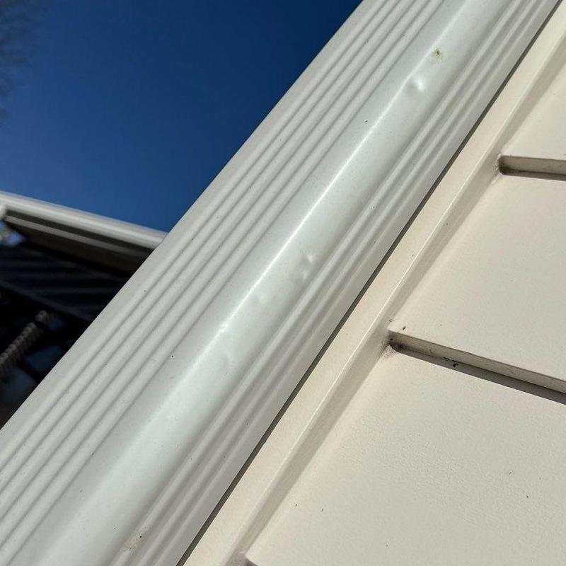 Metal gutter with hail damage dents on roof edge