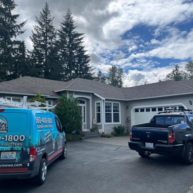Asphalt shingle roof on residential home with service vehicles Asphalt shingle roof on residential home with service vehicles