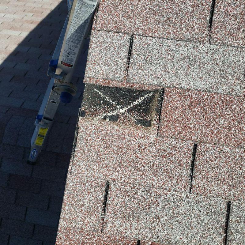 Wind-damaged roof shingle marked with chalk X Wind-damaged roof shingle marked with chalk X