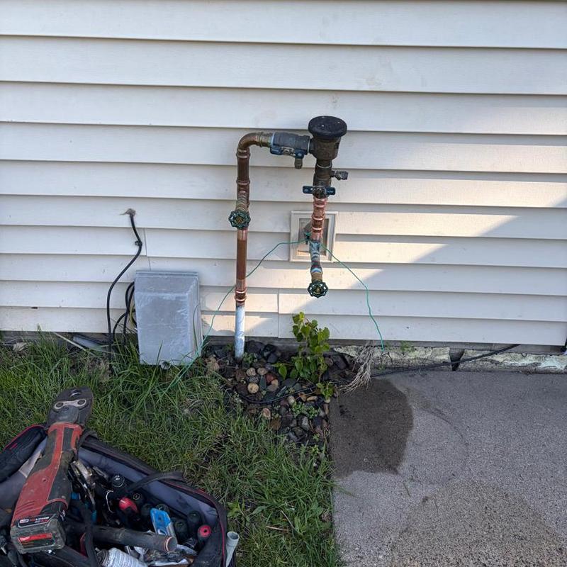 Irrigation vacuum breaker and copper piping near house siding