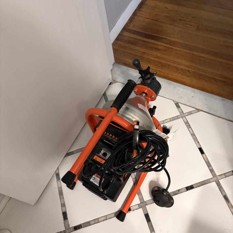 Tub drain power snake with electrical cord on tile floor