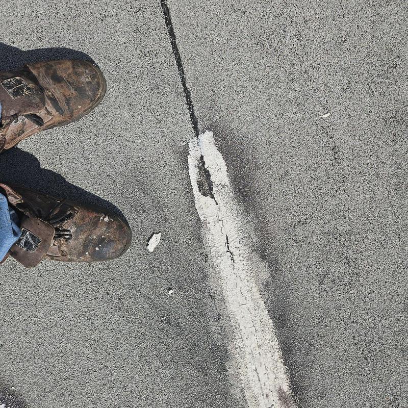 Flat roof with severe cracking near worker's boots Flat roof with severe cracking near worker's boots