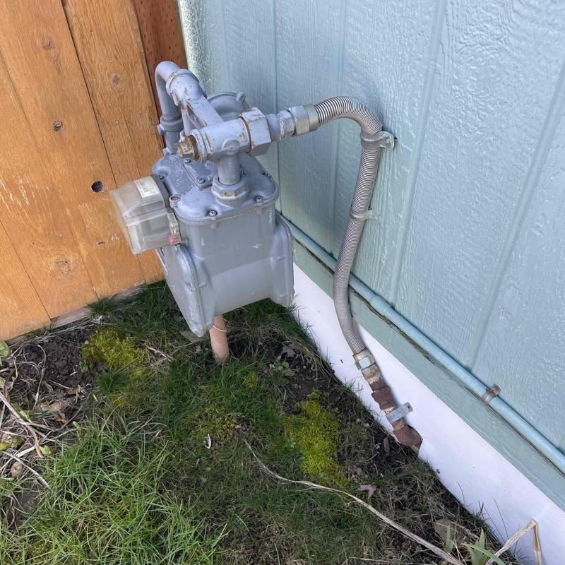 Gas meter and flexible gas line installation near house wall