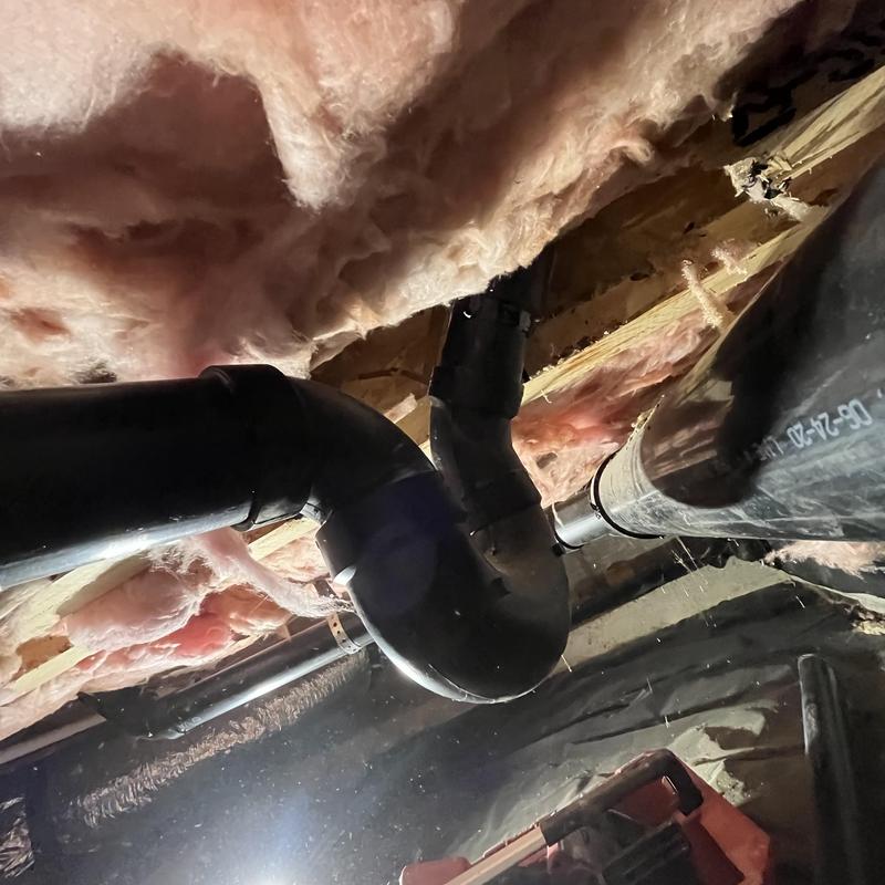 Shower drain piping with new elbow fitting in basement ceiling