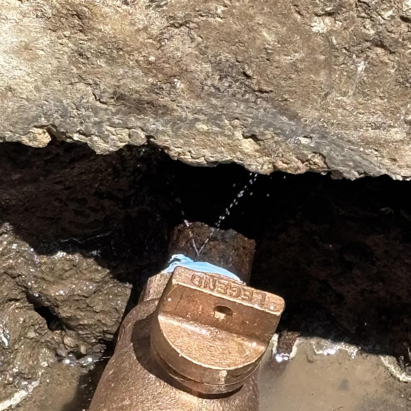 Main waterline pipe leak under concrete slab with water spraying