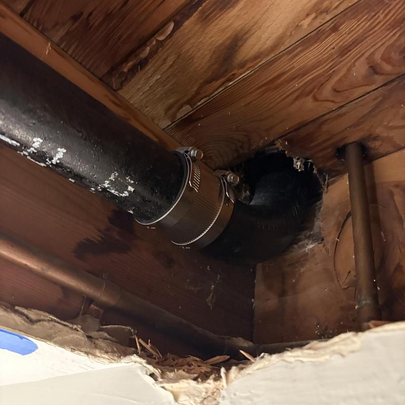 Cast iron drain pipe with new couplings installed under house beams