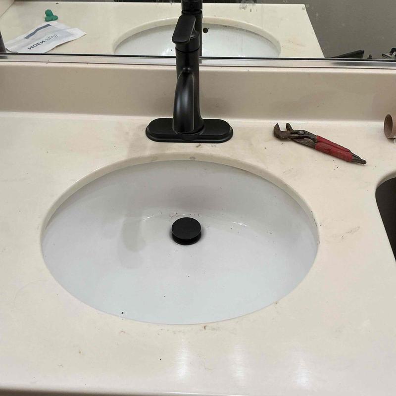 Bathroom sink faucet with installed black pop-up drain