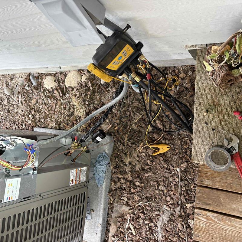 HVAC unit with manifold gauge and tools on ground