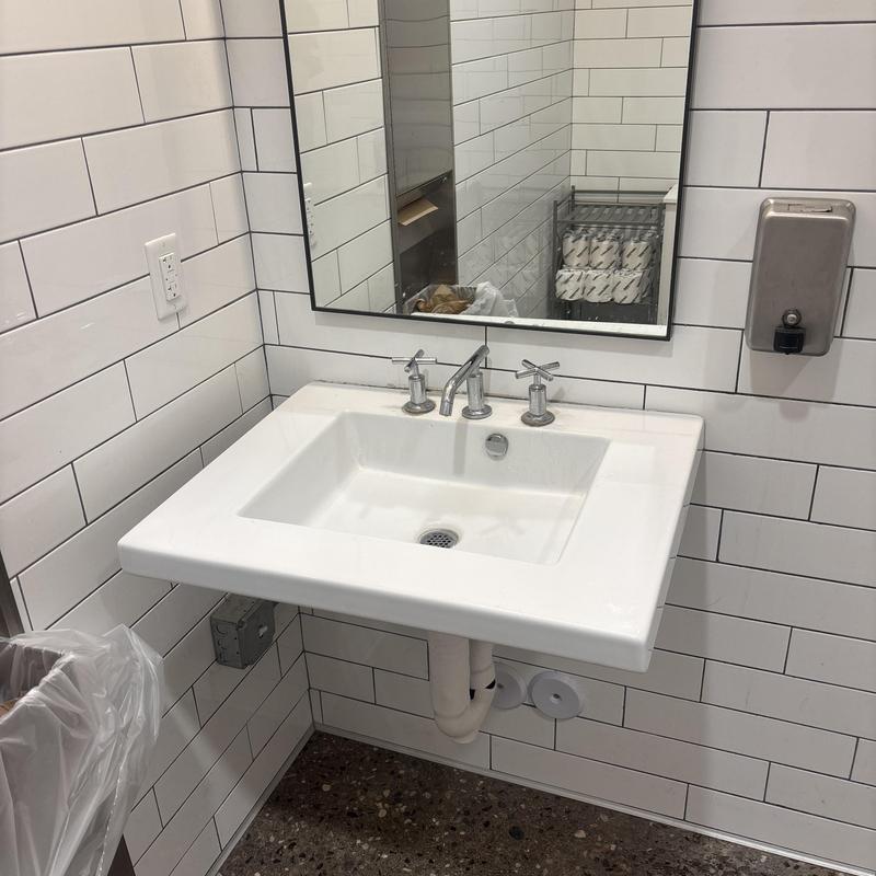 Bathroom sink faucet and drain pipes in tiled restroom