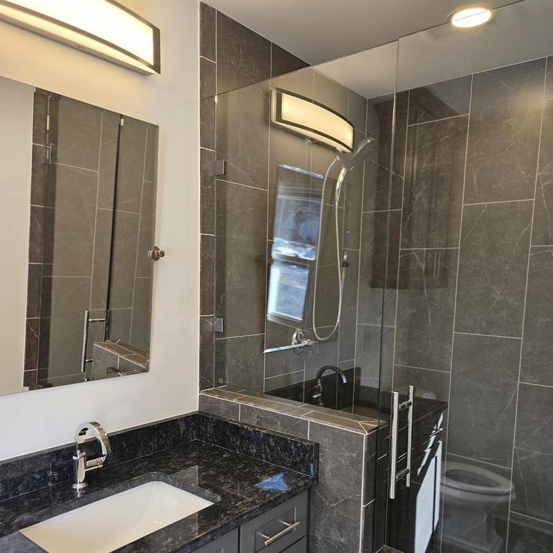 Glass shower enclosure and vanity with dark countertop Glass shower enclosure and vanity with dark countertop