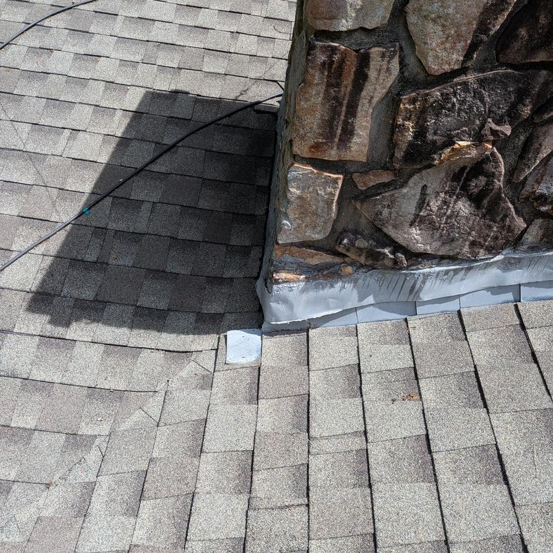 Chimney flashing on asphalt shingle roof with stonework
