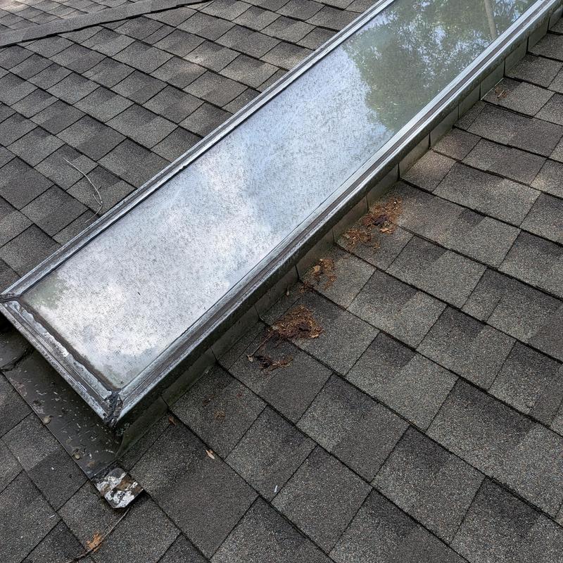 Skylight flashing with worn shingles on roof