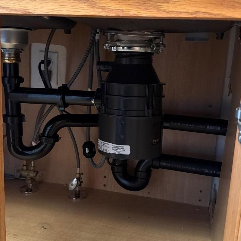 Garbage disposal with relocated plumbing lines under sink