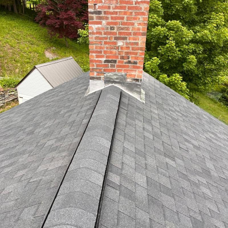 Asphalt shingle roof with brick chimney flashing near trees Asphalt shingle roof with brick chimney flashing near trees