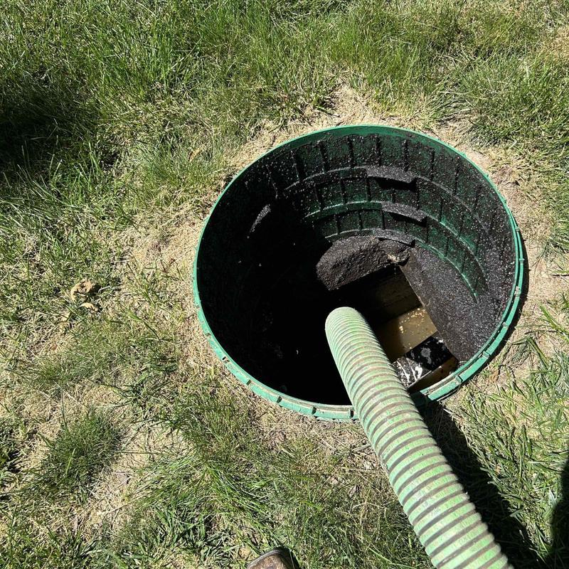 Septic tank pumping with green suction hose in grass