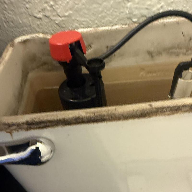 Toilet fill valve with red cap inside tank